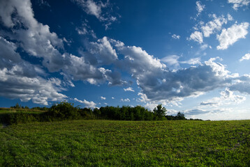 Letni popołudniowy nostalgiczny słoneczny krajobraz z pagórkami polami i zaroślami.  Lato to czas wędrówek  wśród naturalnego środowiska jakie stwarza wiejski krajobraz. © JDziedzic
