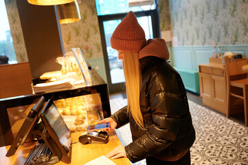 Woman paying with phone at bakery checkout counter
