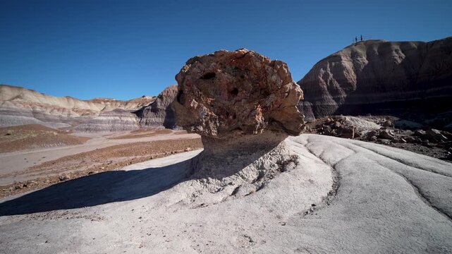Mature woman enjoys hiking in Blue Mesa of Petrified Forest National Park, observing interesting rock formations and the landscape.