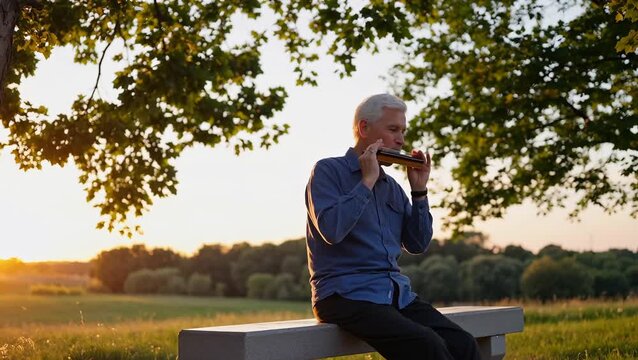 Elderly Man Playing Harmonica in Nature During Sunset