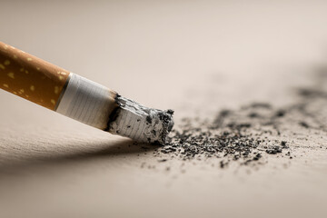 Obraz premium A cigarette lies on a clean surface, burnt ash scattered around, sharp shadows emphasizing the stark reality of smoking addiction and its dangers