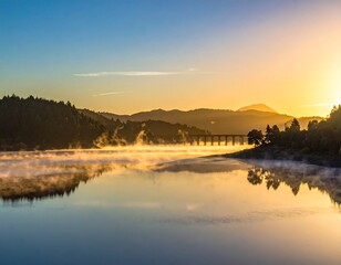 Fototapeta premium Sunrise over a calm lake, with mist and mountains