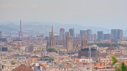 Obraz premium Aerial view on the city of Barcelona, with apartment buildings and skyscrapers on a cloudy day.