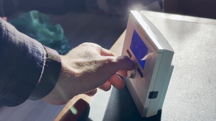 Male hand adjusting digital room thermostat with blue backlit LCD on desk, setting comfort temperature for home heating, HVAC control, energy efficiency concept, with french text