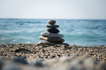 Balanced zen stone tower creating a serene cairn structure on a peaceful pebble beach, with the tranquil blue sea and sky providing a calm background for meditation