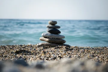 Fotobehang Rustgevend Balanced zen stone tower creating a serene cairn structure on a peaceful pebble beach, with the tranquil blue sea and sky providing a calm background for meditation  © batuhan toker