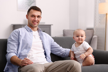 Fototapeta premium Happy father with his cute baby on sofa at home