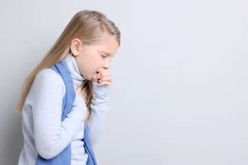 Little girl coughing on light background, space for text. Cold symptom