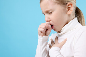 Little girl coughing on light blue background, closeup with space for text. Cold symptom
