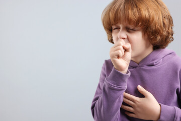 Little boy coughing on light background, space for text. Cold symptom