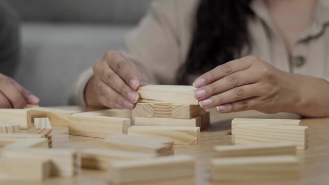 People reassembling a wooden block tower during a tabletop game, focusing on balance, cooperation, and relaxed social play at home.