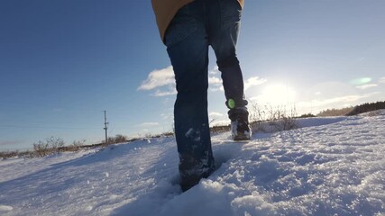Close view of man walking in snow while wearing warm winter boots. Slow motion winter scene with sunlight reflections and cold outdoor conditions in Canada.