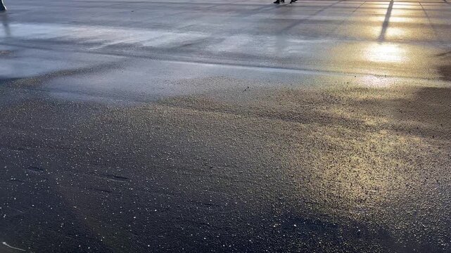 Deicing chemicals on the street in winter. Salt grains on icy sidewalk, asphalt with rock salt in cold season. Slippery road sprinkled with technical salt and calcium. Prevent slipping concept