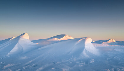 Snowy mountain peaks visible in the distance under a clear blue sky at dusk