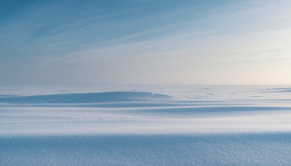 Fototapeta premium A serene landscape of a frozen lake with distant hills under a blue sky with wispy clouds