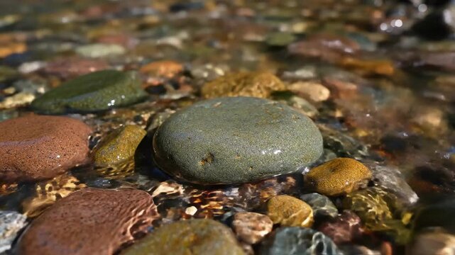 Smooth, wet river rocks and pebbles submerged in clear, flowing water showing natural textures and colors