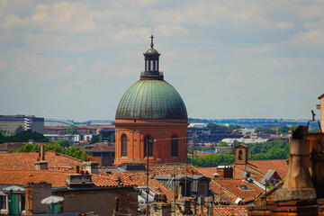 A prominent dome Grave dominates the skyline of Toulouse, France, showcasing classic architecture. Red rooftops extend across the city, bathed in sunlight during a clear day