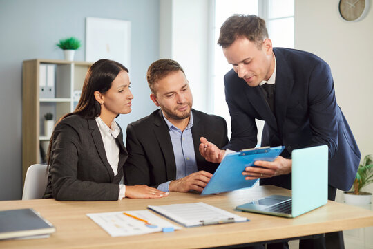 Couple communicates with a real estate agent or consultant during an office meeting, discussing briefing and insurance. Business conversation emphasizes the client-consultant relationship.