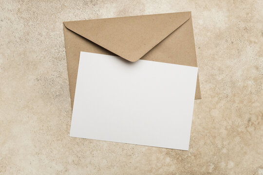Blank white card mockup with a brown envelope on a textured beiege background, ideal for invitations, greetings, or personal messages, showcasing minimalistic design and copy space