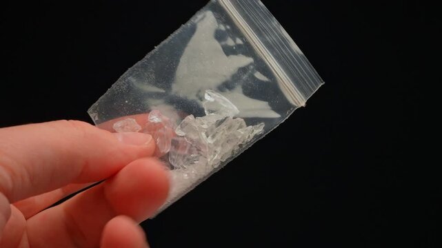 Drug dealer showing Fentanyl Crystal meth or Crack Cocaine for sale and distribution. Drug trafficking and addiction crises. Crystals use in glass tube or stems and primarily smoking or as powder.