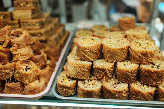 Close up view of spiral shaped kataifi pastries with nut filling, resembling cinnamon rolls, displayed in a traditional sweet shop in Bosnia and Herzegovina. Rich texture and handmade dessert concept.