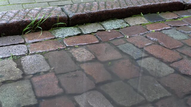 A puddle in a vintage cobblestone street, close-up video.