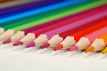New wooden colored pencils of rainbow colors, perfectly sharpened, lie on table