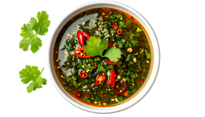 Overhead shot of a white bowl filled with a vibrant green herb sauce, chili flakes