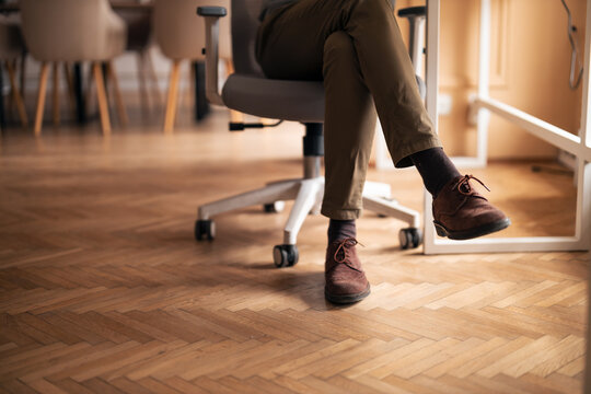 Office Worker Relaxing in Ergonomic Chair, Crossing Legs, Brown Shoes on Wooden Floor