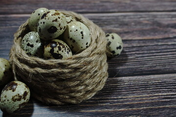 Obraz premium Fresh quail eggs arranged in a coiled jute rope nest on a dark wooden surface