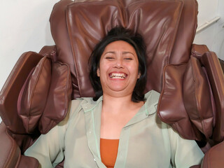 Closeup face of young asian woman is getting a leg massage with an electric massage chair to relieve aches and pains.