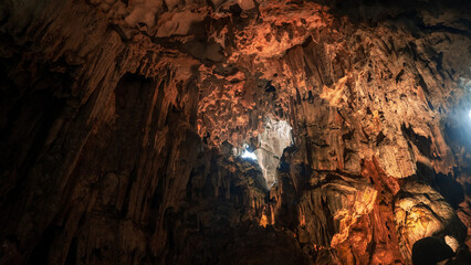 Vast interior of a large cave with massive stalagmites and flowstone under a textured ceiling