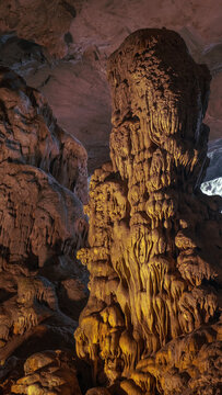 Vast interior of a large cave with massive stalagmites and flowstone under a textured ceiling