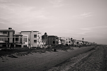 Fototapeta premium Pastel sunset sky above a long row of beachfront homes and sandy shoreline in Sunset Beach, California, capturing calm coastal living at dusk.