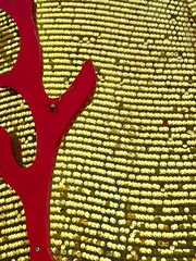 Christmas decoration - Multiple shiny red baubles hanging against a background of gold sequins.