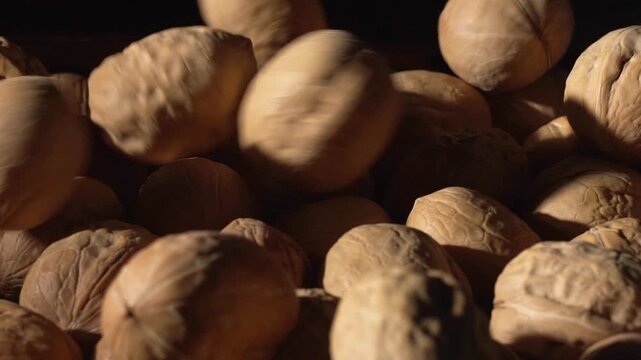 Close-up footage of whole walnuts and walnut kernels, highlighting natural textures, rich color contrast, and detailed surfaces for food and nutrition themes.