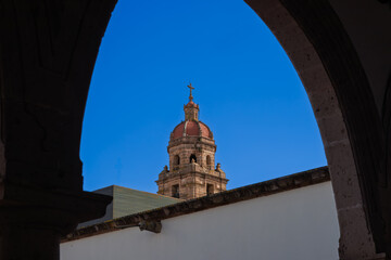 Bell tower of San Agustin Rectoria seen through colonial arch in Morelia, Mexico
