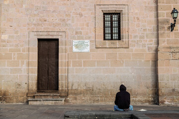 Young man sitting in front of the historic Archbishopric building entrance in Morelia, Mexico