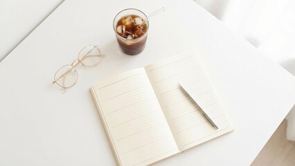 Open notebook with lined pages a pencil eyeglasses and iced coffee on a white table