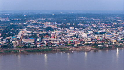 Aerial drone view of Savannakhet city lights turning on at twilight. The street grid and urban layout are visible as the town transitions from day to night.