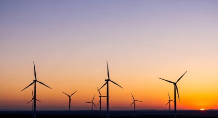 Fototapeta premium Silhouettes of wind turbines against a vibrant sunset sky with gradient colors