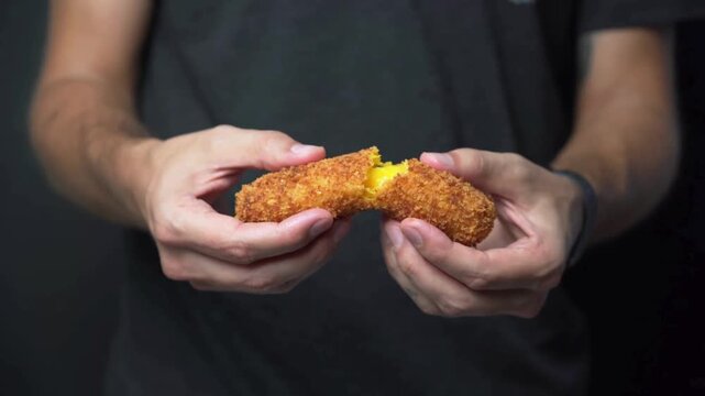 food blogger pulls a crispy mozzarella croquette apart medium shot.