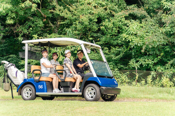 Male and female golfers riding golf carts at a golf course