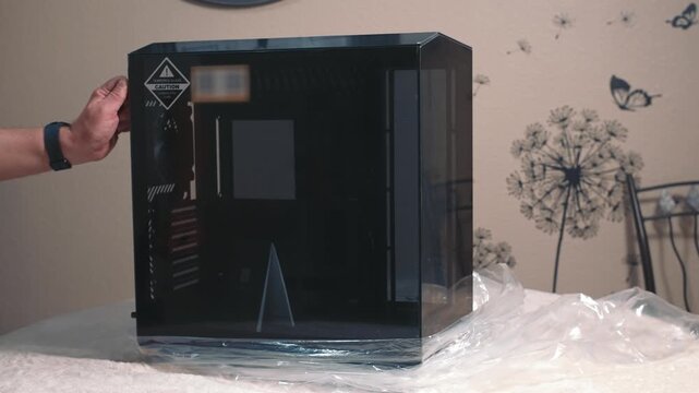 Man opens tempered glass side panel of computer case during assembly