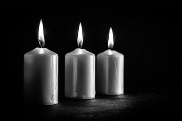 Three lit white pillar candles glowing softly against a dark background