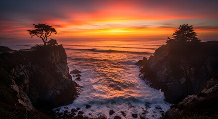 Dramatic sunset over rocky coastline with cypress trees and crashing waves ocean