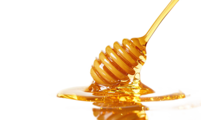 Golden Honey Dripping from a Wooden Dipper on Black Background