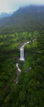 Aerial vertical view of Bahuli Waterfall surrounded by dense green forest near Igatpuri, Maharashtra. Misty mountains, monsoon greenery and natural landscape captured from above.