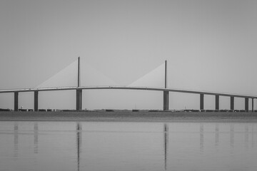 The iconic Sunshine Skyway Bridge spanning Tampa Bay, Florida under a dramatic blue sky. Warm sunset light and sweeping clouds highlight the modern architecture and elegant engineering of this famous 