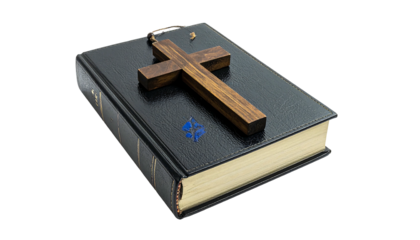 A closed, leather-bound book, with a large wooden cross resting on its cover, isolated against a solid black background